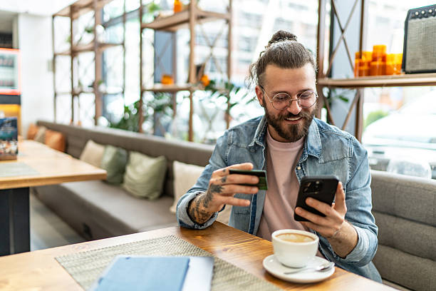istock Young man making online payment using credit card in cafe 2234741073