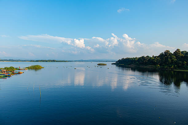 istock Tranquil Kaptai Lake view featuring a green forested shore, scattered water plants, and serene blue skies. 2234741275
