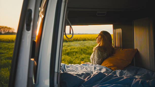 istock Woman Leaning on Camper Van Bed while Standing Outside at Sunset 2234744475