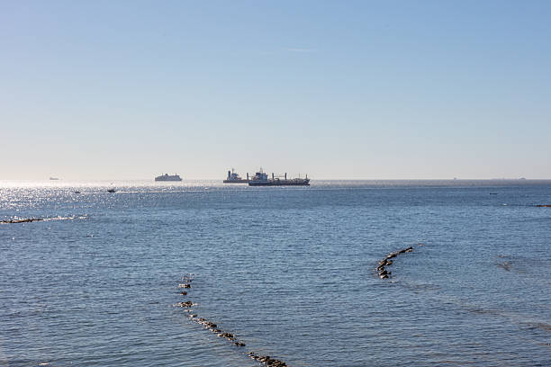 Gibraltar coast with rocky shore and cargo ship. Gibraltar, spain. september 2025. High quality photo