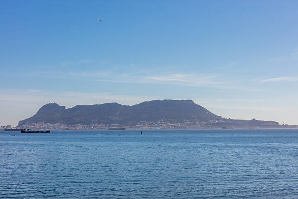 Gibraltar coast with rocky shore and cargo ship. Gibraltar, spain. september 2025. High quality photo