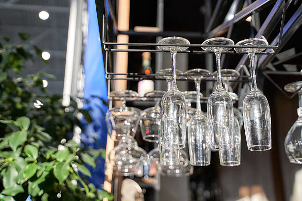 istock Empty wine glasses hanging upside down at a bar with sunlight and greenery 2234756007