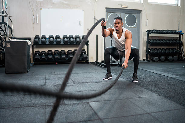 istock Determined Athlete Using Battle Ropes During High-Intensity Workout In Modern Fitness Center 2234758247