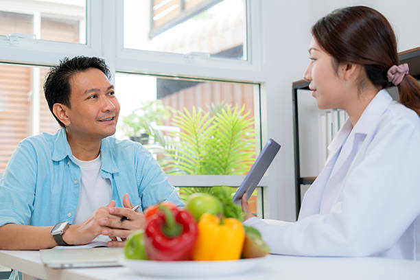 istock Asian nutritionist using tablet to explaining personalized meal plan with AI to patient during healthcare consultation, healthy lifestyle, woman dietitian showing nutrition plan with AI on tablet. 2234780191