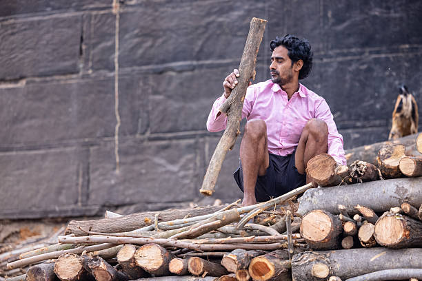 Varanasi, Uttar Pradesh, India - March 2024: Portrait of an male labour working at the wood warehouse for the cremation of bodies at the manikarnika ghat in varanasi.
