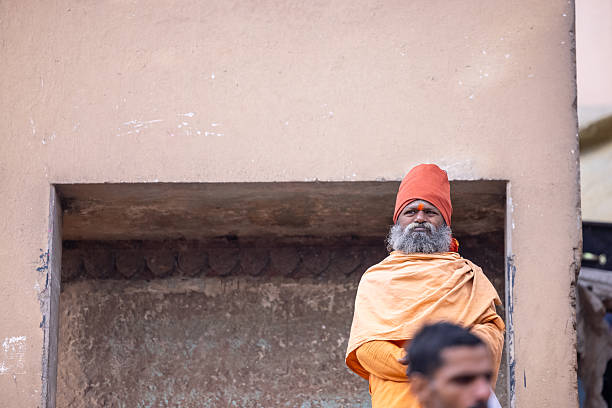Varanasi, Uttar Pradesh, India - March 2024: Portrait of an old holy brahmin priest in traditional dress sitting at the ghat near ganges in varanasi.