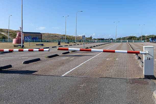 istock Empty parking lot with a barrier gate, featuring clear blue skies and distant greenery, illustrating a serene and unoccupied outdoor space 2234795120