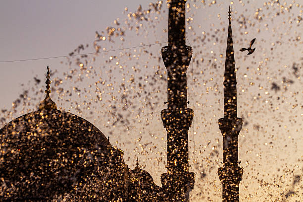 Silhouette of the Sultan Ahmed Mosque (Blue Mosque) in Istanbul, with water splashes from a fountain in the foreground, captured at sunset