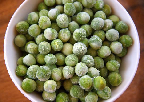 istock Frozen Green Peas in White Bowl on Wooden Table, Close-up, Copy Space 2234797599