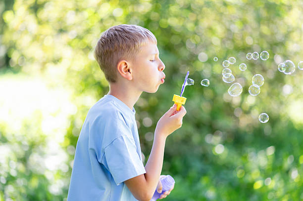 istock Teen boy blowing soap bubbles in summer park 2234797864