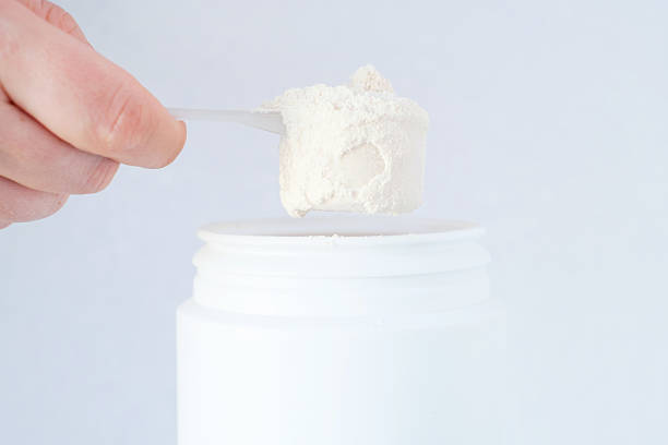 istock Protein powder in scoop from plastic jar side view on gray background close-up. 2234799398