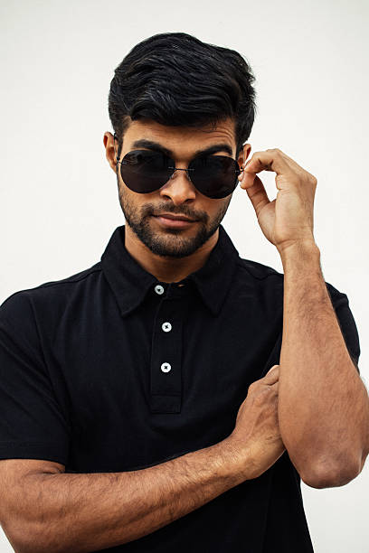 Confident man in sunglasses and black polo shirt on light background