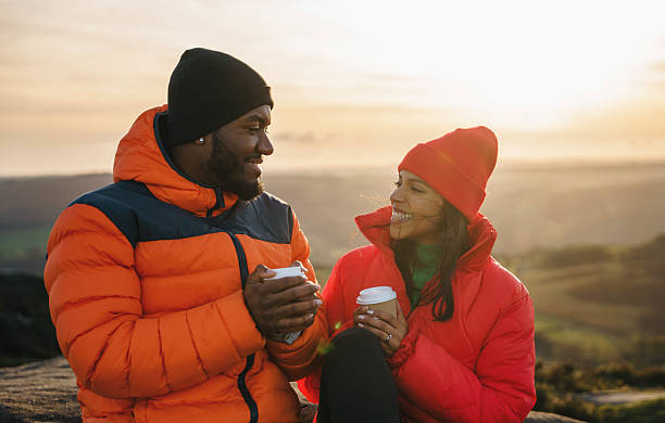 istock Couple enjoys warm drinks while watching the sunrise on a mountain peak in a cool winter morning 2234800906