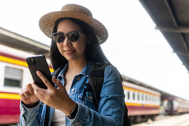 istock Young asian traveler backpacker woman using smartphone looking map and checking train schedule and browsing social media online at train station, solo travel female lifestyle and internet technology. 2234802540