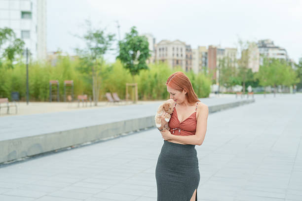 istock A woman is holding a small dog on a sidewalk 2234803496