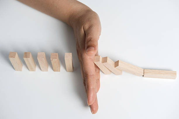 istock Hand stopping or preventing a falling block. Concept of hedging. 2234803614