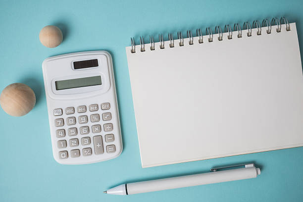 istock Workspace with empty notebook, calculator, pen and wooden ball on blue background. 2234803630