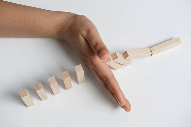 istock Hand stopping or preventing a falling block. Concept of hedging, risk elimination. 2234803644