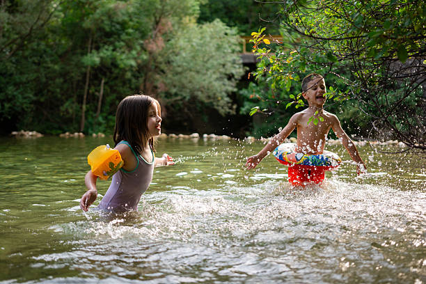 Two young children are playing and splashing in a river on a summer day, enjoying their vacation