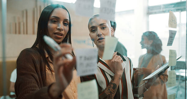 istock Business women, planning or schedule with sticky note for brainstorming ideas or reminder in office. Female people, employees or team thinking with mindmap for project, agenda or tasks in workplace 2234805969