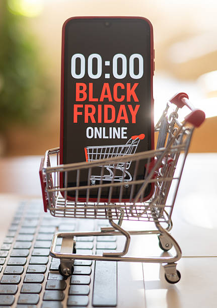Shopping cart carrying a smartphone displaying black friday online countdown timer placed on a laptop keyboard represents online shopping and e-commerce deals