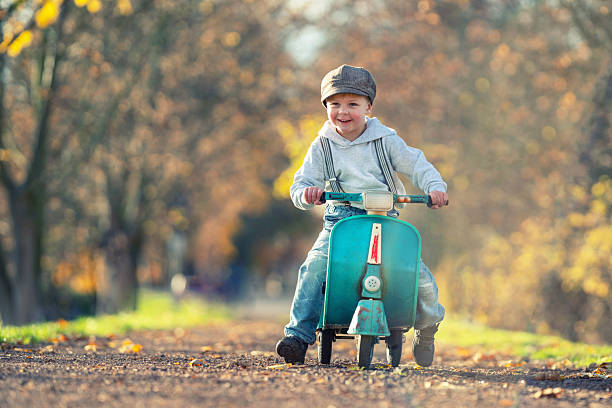happy child is playing in autumn park with scooter