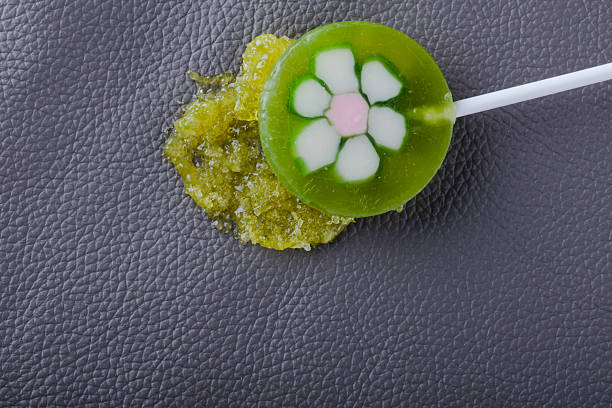 A green sticky lollipop, a dip on the upholstery of a gray leather sofa. Concept of daily stains and routine cleaning. Spot-cleaning upholstery or carpets. top view.