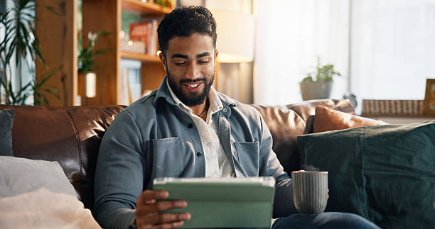 istock Happy man, tablet or watching with coffee on sofa for online entertainment or subscription in home. Male person, smile and streaming with technology for movie app, network or connection in house 2234814768
