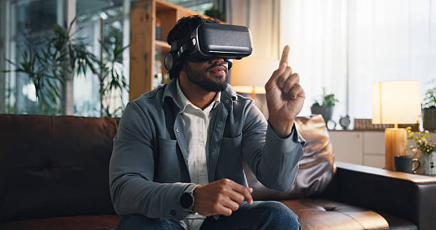 istock Virtual reality, interaction and man on sofa in home for online gaming, metaverse and connection. Gamer, living room and person with vr headset for user experience, simulation and entertainment 2234814822