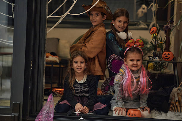 A group of children playing on a Halloween day. They are indoors, playing, dressed up in costumes.