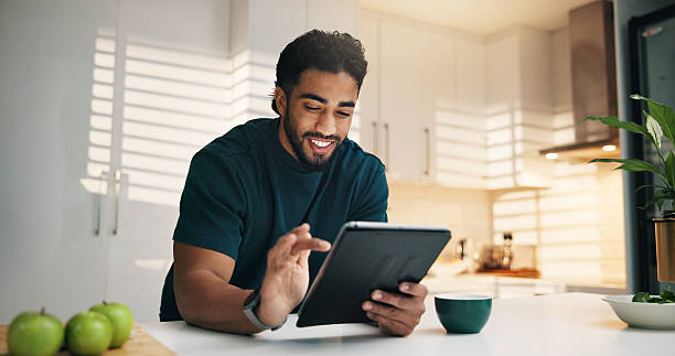 istock Tablet, happy and man with coffee in kitchen in morning with networking, communication or app. Technology, research and male person with cappuccino for texting, contact or social media in apartment. 2234817823