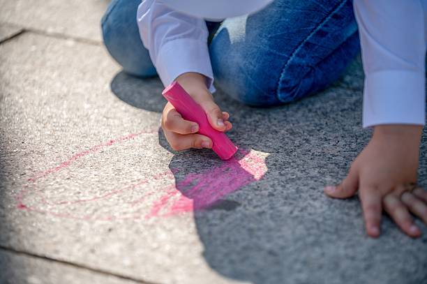 istock Child drawing with pink chalk on pavement. 2234819936