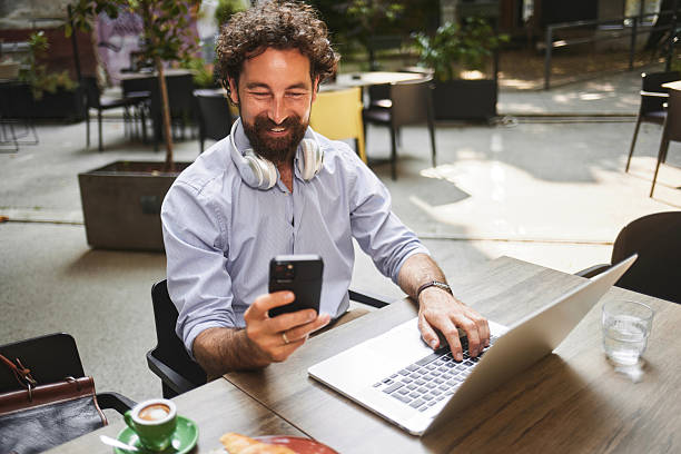 istock Freelancer working remotely from a cafe using laptop and smartphone 2234820228
