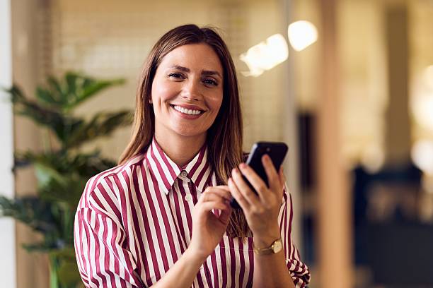 istock Confident Businesswoman Smiling While Using Smartphone in Modern Office Setting 2234821761