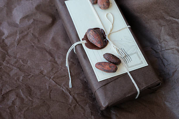 Chocolate parcel with sealing wax. Gift chocolate bars in brown packaging on brown crumpled wrapping paper. Cocoa beans.