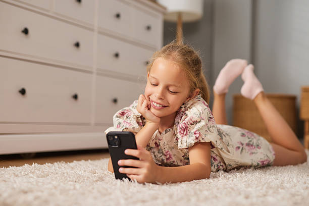istock Child enjoys time on smartphone while lying on the floor in a cozy room during 2234823837