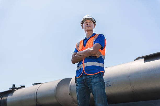 istock Engineer Man Standing by Train Carriages with Arms Crossed on Train Tracks, Industrial Worker with Arms Crossed Overlooking Rail Yard, Man in Hard Hat and Safety Vest by Freight Train 2234827627