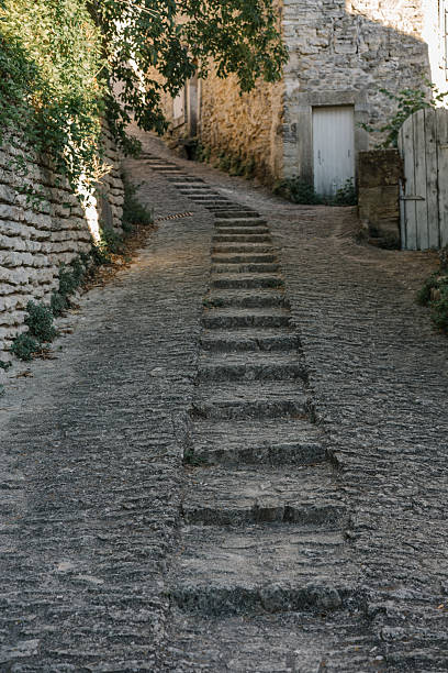 istock A narrow cobbled alleyway with embedded stone steps leading uphill between old stone buildings in a quiet, rustic village. The path is partially shaded by greenery, timeless European vibe 2234828419