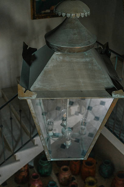 istock Rustic chandelier lantern hanging in a staircase with iron railings, overlooking colorful ceramic jars on the floor. Vintage lighting and eclectic interior design. 2234829122