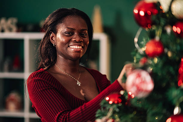 istock Young woman decorating christmas tree at home smiling at camera 2234829318