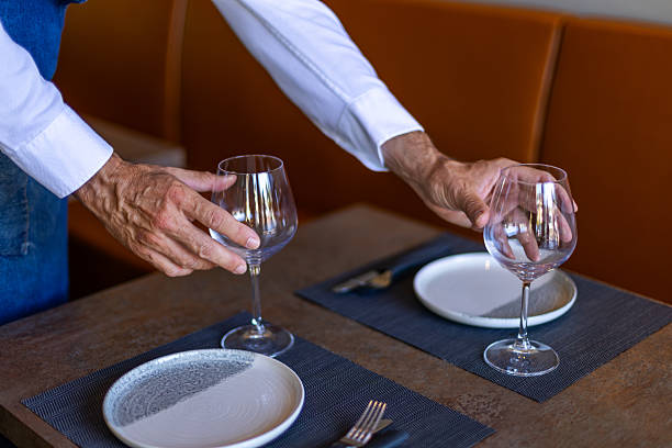 istock Waiter placing wine glasses on restaurant table for dinner service 2234829731