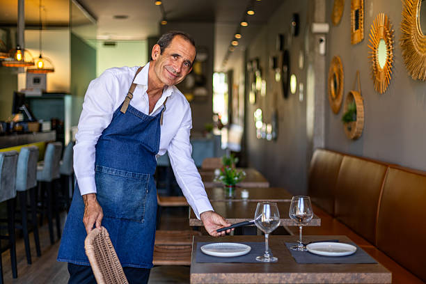 istock Waiter setting a table in a restaurant smiling at camera 2234829742