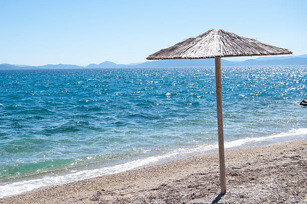 An umbrella on the empty beach. A seashore background with an umbrella. A seascape frame with copy space. Travelling and tourism background.