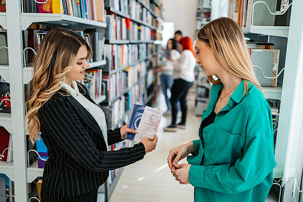 istock Two Female Students Reading A Book In A School Library 2234836536