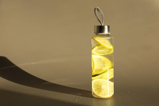 istock Lemon water with lime in bottle on light brown background, space for text 2234838308