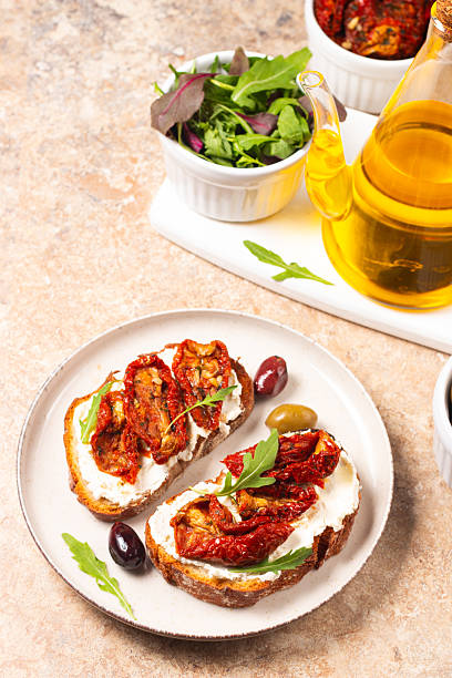 Toast with cream cheese and dried tomatoes. Open sandwich with arugula, bread, tomatoes, olives and oil.