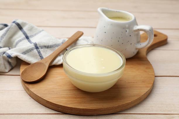 istock Condensed milk and spoon on light wooden table, closeup 2234842099