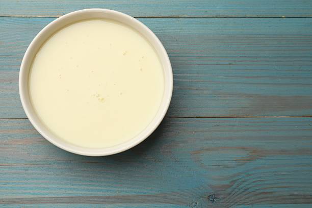 istock Condensed milk in bowl on light blue wooden table, top view. Space for text 2234842112