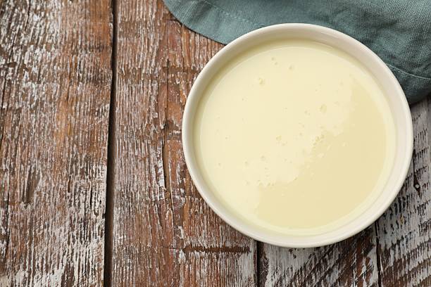 istock Condensed milk in bowl on wooden table, top view. Space for text 2234842134