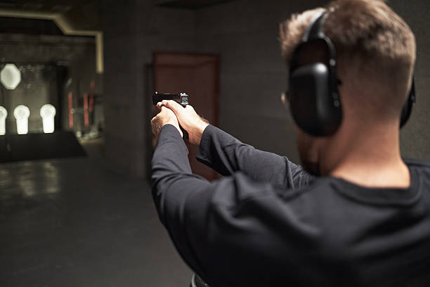 istock Young Adult Man Practicing Shooting Handgun at Indoor Firing Range 2234843965
